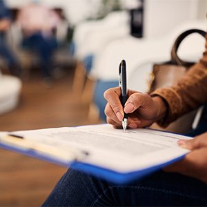 Woman filling out dental insurance form in lobby